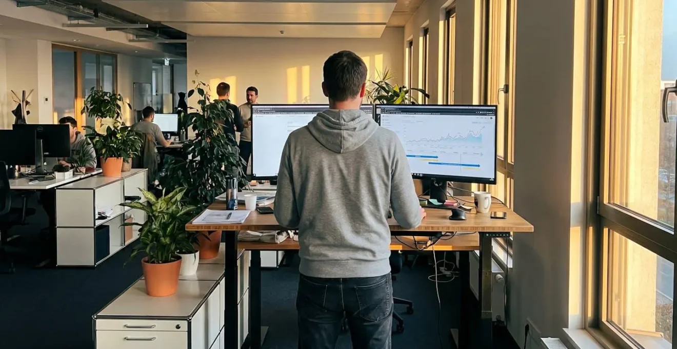 Professional reviewing growth roadmap on computer monitor at standing desk in bright contemporary office